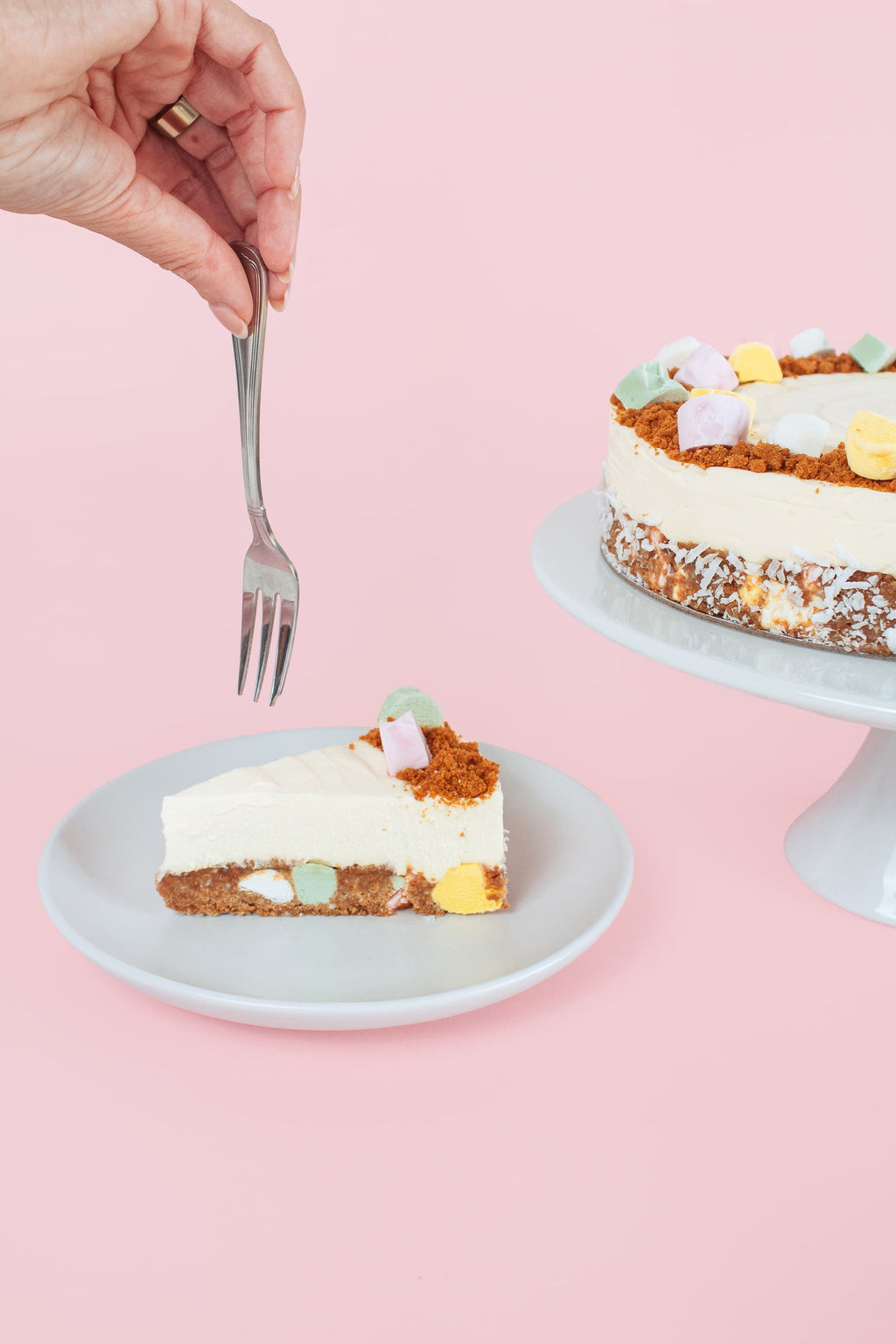 Someone holding a fork above a slice of Lollycake White Chocolate Cheesecake